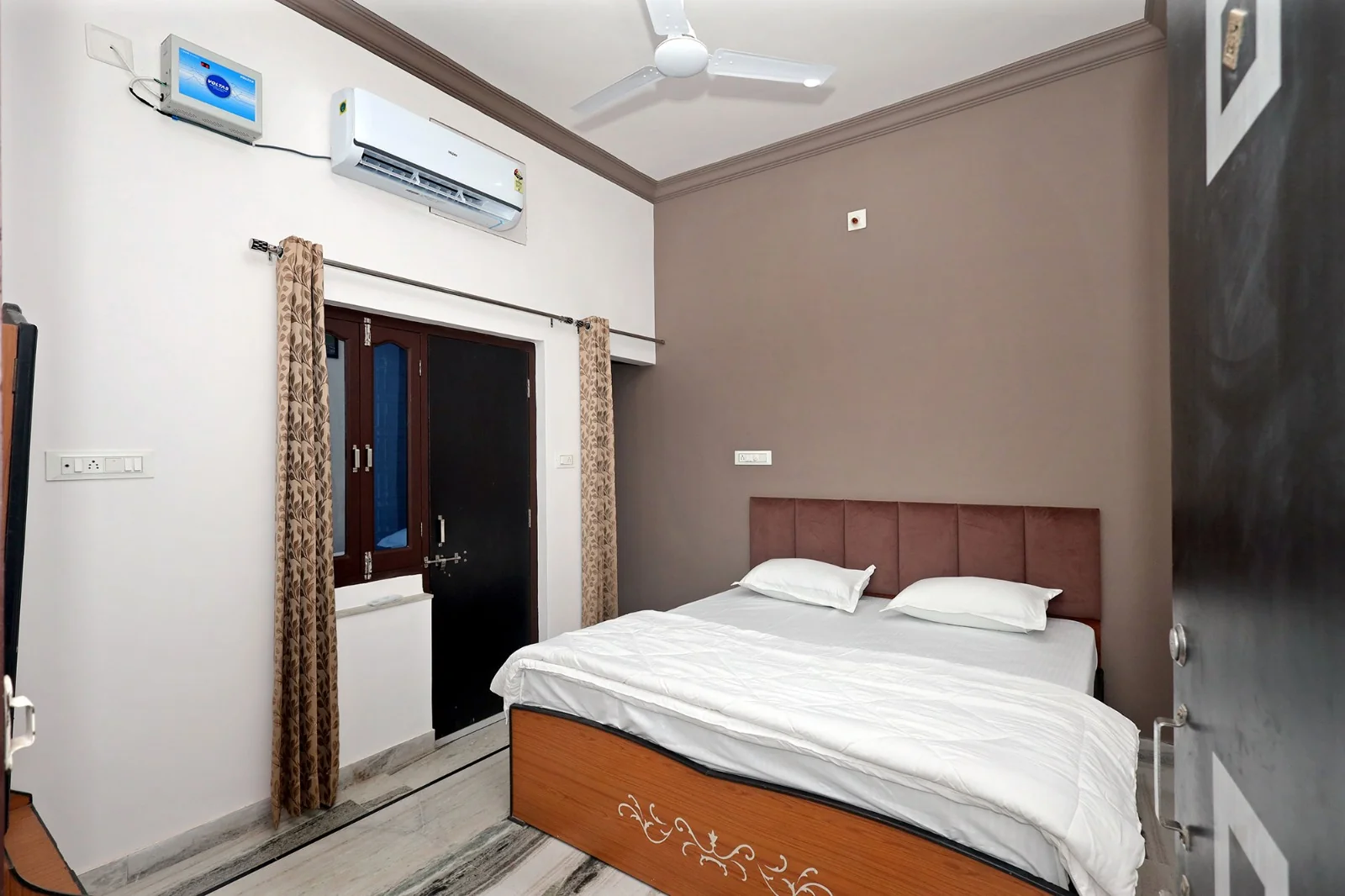 Double bedroom with a queen bed and upholstered headboard at Meeraavi Home Stay, Udaipur